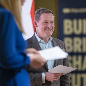 Edited photography of a speaker smiling at a corporate conference in 2025 in Barcelona, Spain.